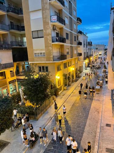 un grupo de personas caminando por una calle por la noche en Suite 55 in centro, en Trani