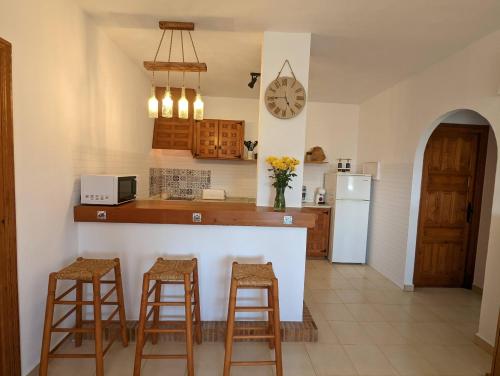 a kitchen with a counter and stools and a refrigerator at PRECIOSA CASA PARA 5 PERSONAS CERCA DE MORAIRA. RACÓ DE LLEVANT. LIVE IT COSTABLANCA in Moraira