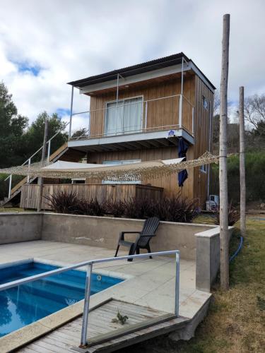 a house with a swimming pool next to a house at al pie de las sierras en villa del lago in Tandil