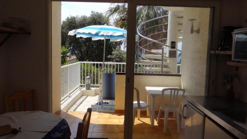a kitchen with a table and an umbrella on a balcony at Residence Funtanella in Sagone