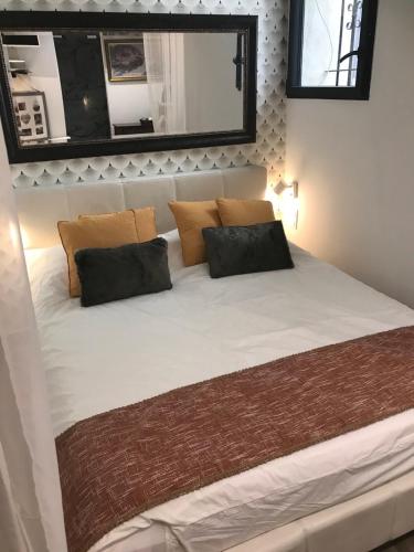 Elle comprend un grand lit blanc avec des oreillers et un miroir. dans l'établissement Chambre via Natina, à Saint-Germain-en-Laye