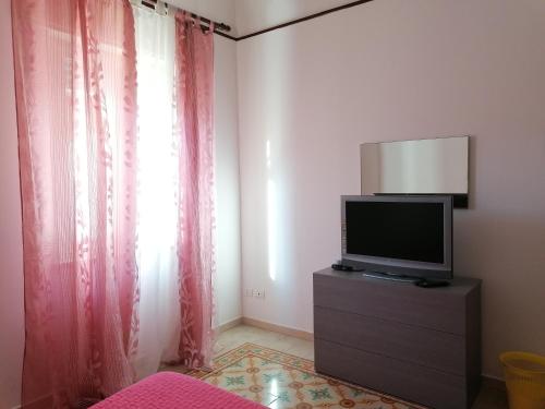 ein Schlafzimmer mit einem TV auf einer Kommode mit einem Fenster in der Unterkunft Tulipano in Trapani