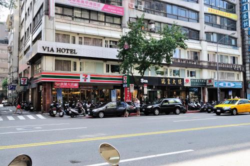 台北市にあるヴィア　ロフト　ホテルの建物前にバイクが停まる賑やかな街道