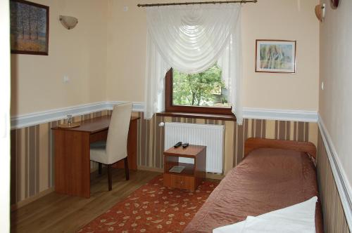 a bedroom with a bed and a desk and a window at Hotel Restauracja Redos in Nysa