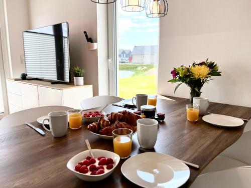 a wooden table with a breakfast of fruit and orange juice at Ferienhaus Fischkopf in Büsum