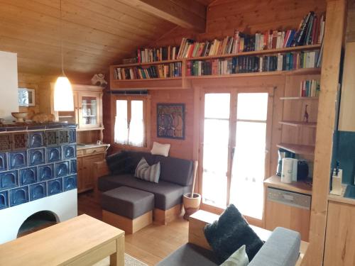 a living room with a couch and a kitchen with books at Hüttenzauber Ferienwohnung mitten im Nationalpark in Lindberg