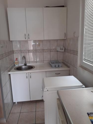 a small kitchen with white cabinets and a sink at Villa Angelina in Kumbor