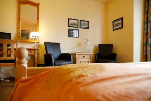 a bedroom with two chairs and a desk and a bed at Landhotel Hofgut Battenberg in Battenberg