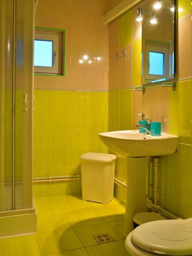 a yellow bathroom with a sink and a toilet at Apartament Deny in Sulina