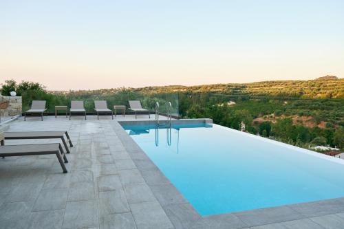 a swimming pool with chairs and a view of a hill at Villa Olive Valley in Loutrákion