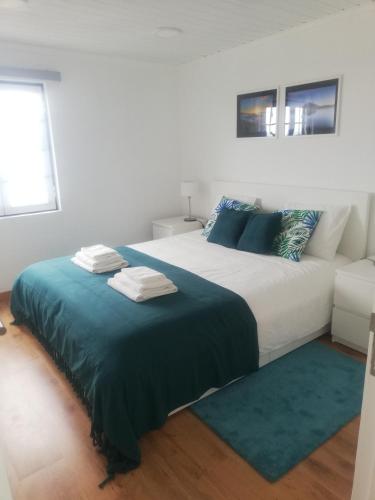 a bedroom with a large bed with a blue blanket at Vitamin Sea in São Roque do Pico