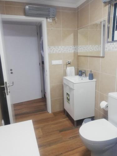 a bathroom with a white toilet and a sink at Vitamin Sea in São Roque do Pico