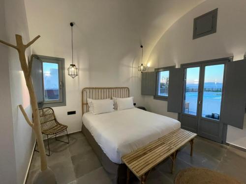 a bedroom with a bed and a bench and windows at Anemi Vine Villas in Foinikiá