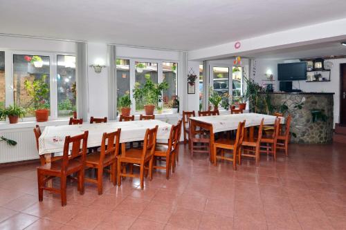 a dining room with white tables and wooden chairs at Pensiunea Maria in Moieciu de Jos