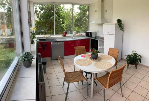 une cuisine avec une table et des chaises dans une pièce dans l'établissement Charmante maison avec cheminée, grand jardin et boxe chevaux, à Saint-Hilaire-sur-Helpe