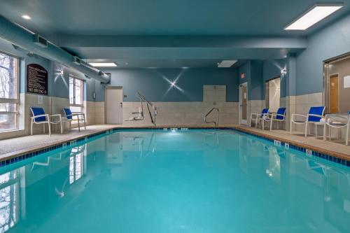 a swimming pool with chairs and tables in a building at Holiday Inn Express Hotel & Suites Woodbridge by IHG in Woodbridge