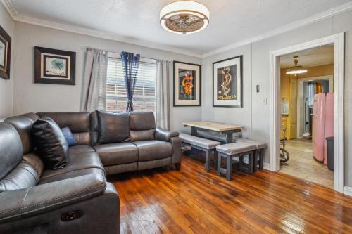 a living room with a leather couch and a table at The Old Downtown Historic Grand Prairie House home in Grand Prairie