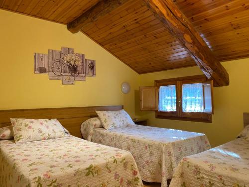 a bedroom with two beds and a wooden ceiling at Hostal Can Josep in Sort