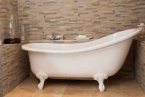 a white bath tub in a bathroom with tiles at A Whale of a Time in Fish hoek