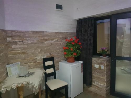 a room with two tables and a table with a plant on a refrigerator at Casa Lipianu in Târgu Jiu