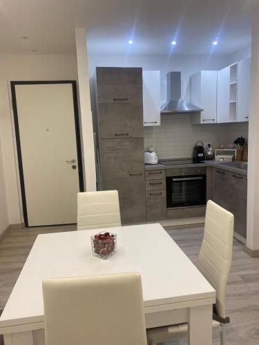 a kitchen with a white table and white chairs at Bnb apartment Ferrara in Udine