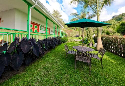a table and chairs with an umbrella in the grass at Hotel Mirador de Boquia Salento in Salento