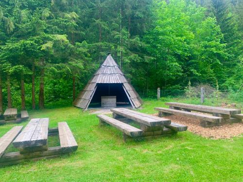 a group of benches in a field with a teepee at Črjanski Raj in Črna na Koroškem