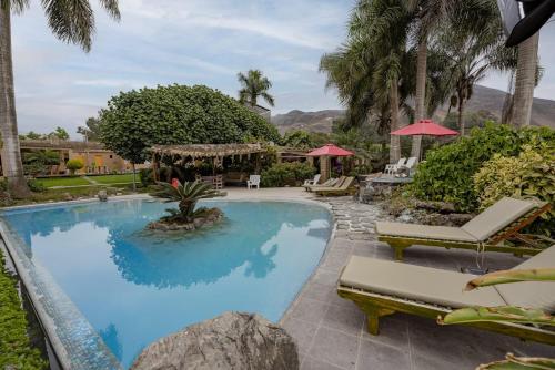 a swimming pool with lounge chairs and umbrellas at Casa Boutique QX- Pachacamac in Pachacamac