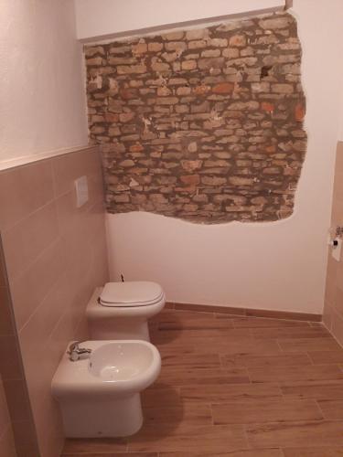 uma casa de banho com um WC e uma parede de pedra em cascina carlo em Aie