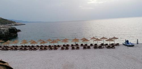 a group of chairs and umbrellas on a beach at Sky Apartments in Sarandë