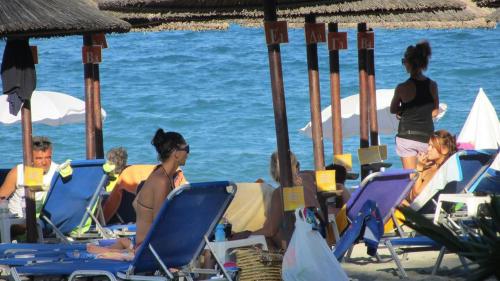 eine Gruppe von Menschen, die am Strand auf Stühlen sitzen in der Unterkunft Sun Studios Pieria in Paralia Skotinas