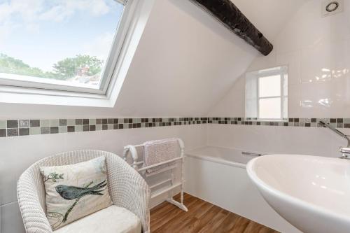 a bathroom with a chair and a tub and a sink at Brincliffe Cottage in Robin Hood's Bay