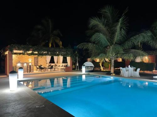 a swimming pool at night with a resort at Villa Le Petit Paradis Saly Boutique Hotel in Ngaparou