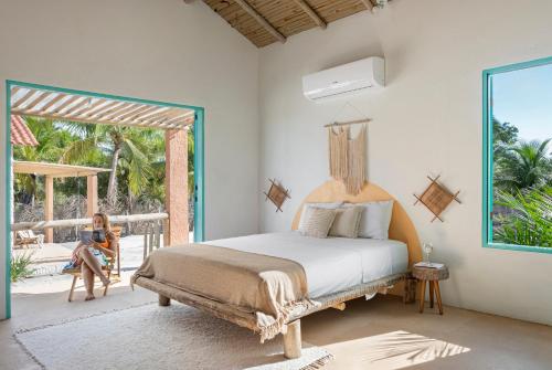 a woman sitting in a chair in a bedroom with a bed at Vila da Falésia in Corumbau