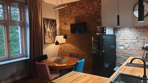 a kitchen with a table and a black refrigerator at Apartament Wysoka Brama 1/4 in Gryfice