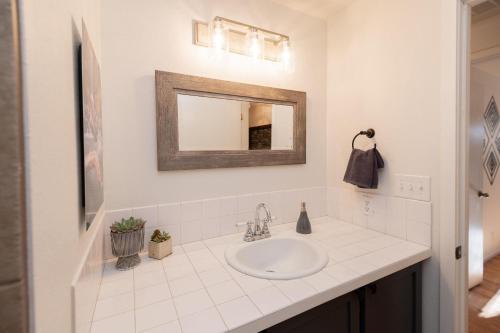 a white bathroom with a sink and a mirror at BEkiND Cottage in Bend