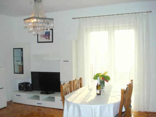 uma sala de jantar com uma mesa branca e um lustre em Guest House Adria em Senj