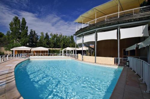 a large swimming pool in front of a building at Hotel Le Phoebus Garden & Spa in Gruissan