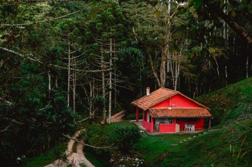 una pequeña casa roja en medio de un bosque en Sítio das Hortênsias Chalés en Conceição da Ibitipoca