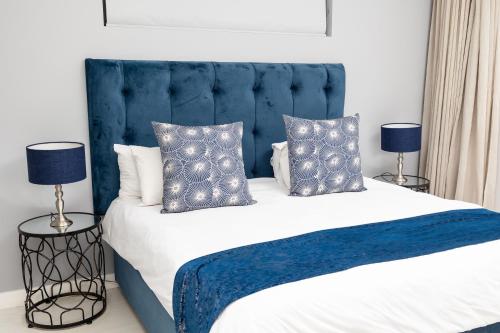uma cama com cabeceira azul e almofadas em One Hyde Park - Sandton em Joanesburgo