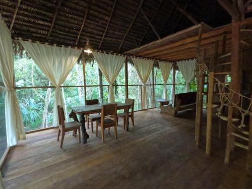 a dining room with a table and chairs and windows at Enchanting Jungle Villa — UMARI in Iquitos