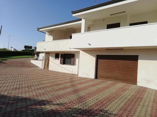 a house with a garage door and a brick driveway at CASA VACANZA DA ZIO NINO in Capo Vaticano