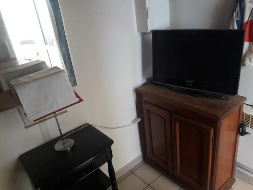 telewizor na drewnianym gablocie z lampką w obiekcie mini maison mini budget w mieście Soulac-sur-Mer