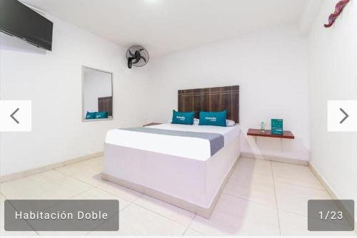 Un dormitorio blanco con una cama con almohadas azules. en Hotel Villa Luna del Llano, en Villavicencio
