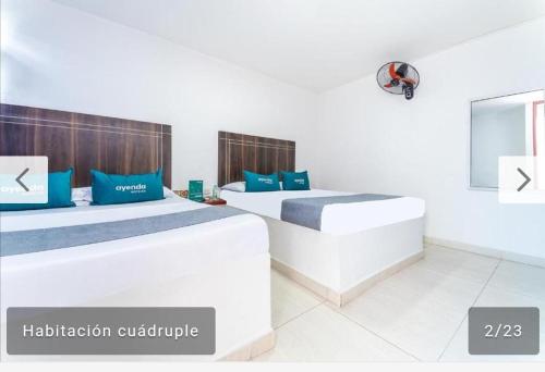 Habitación blanca con 2 camas con almohadas azules en Hotel Villa Luna del Llano, en Villavicencio