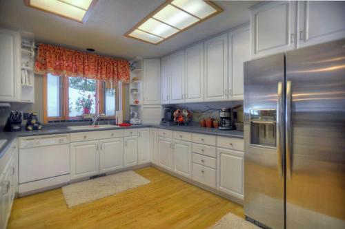 a kitchen with white cabinets and a stainless steel refrigerator at Seven Pines Cabin in Vallecito Lake Area in Bayfield