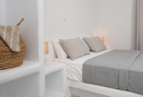 a white room with a bed with pillows and a basket at Vavoulas Village in Mikri Vigla
