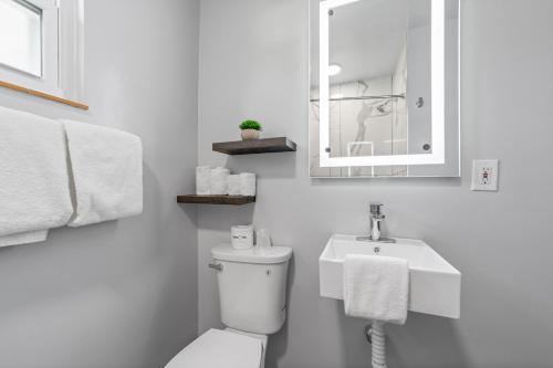 a white bathroom with a toilet and a sink at Glass House Inn Erie Near I-90 & I-79 in Erie