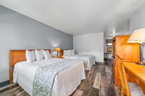 a hotel room with two beds and a desk at Glass House Inn Erie Near I-90 & I-79 in Erie