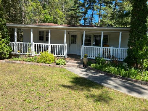 a white house with a porch and a yard at Cheerful beautiful cottage 3 bedroon in Wasaga Beach